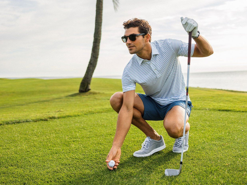 Man on gold course picking up golf ball.