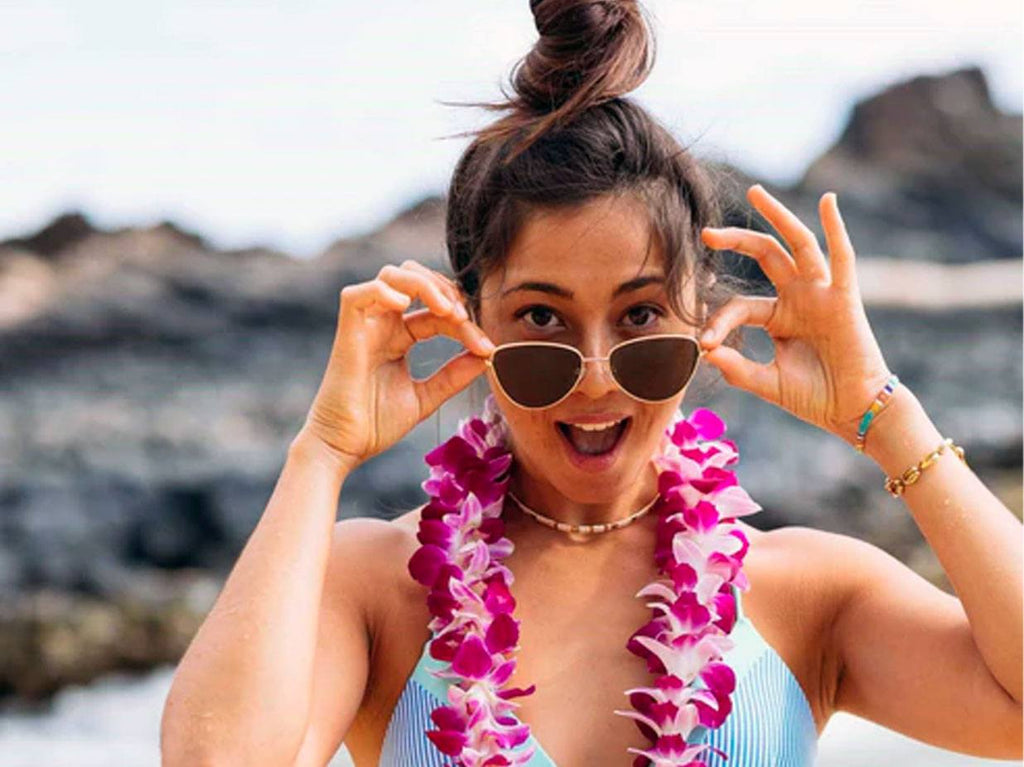 Girl wearing lei and sunglasses and bathing suit.