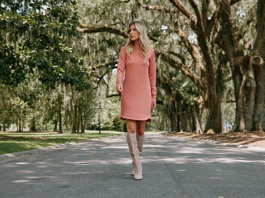 Girl wearing coral dress smiling at camera.