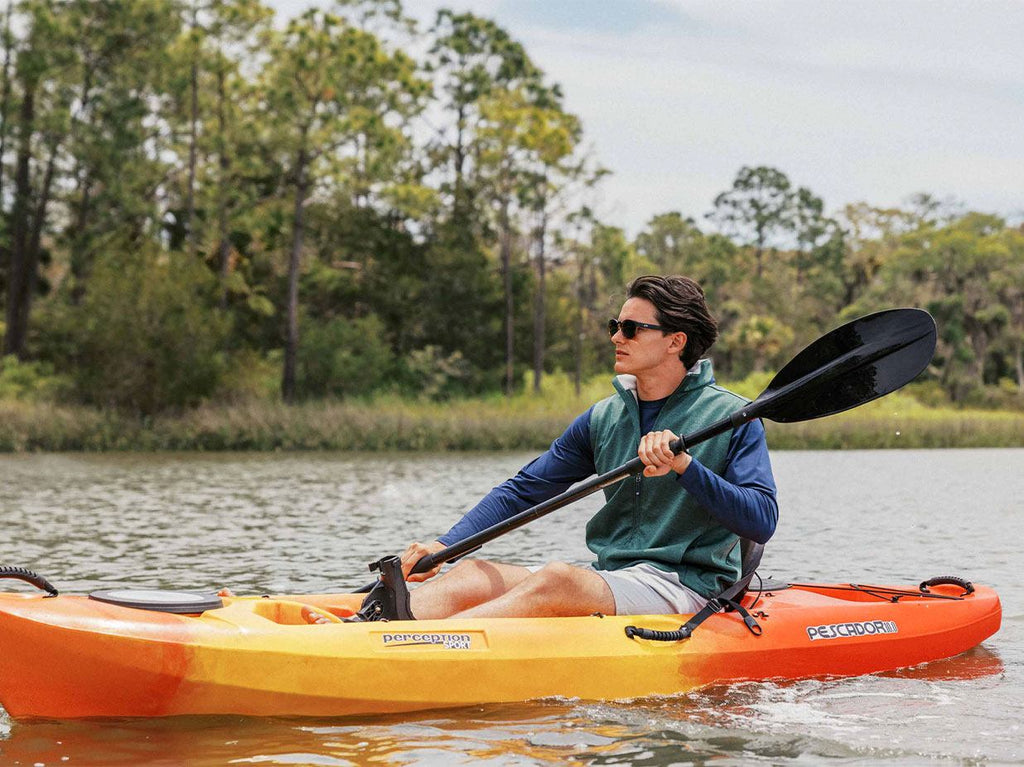 Man kayaking in a marsh.
