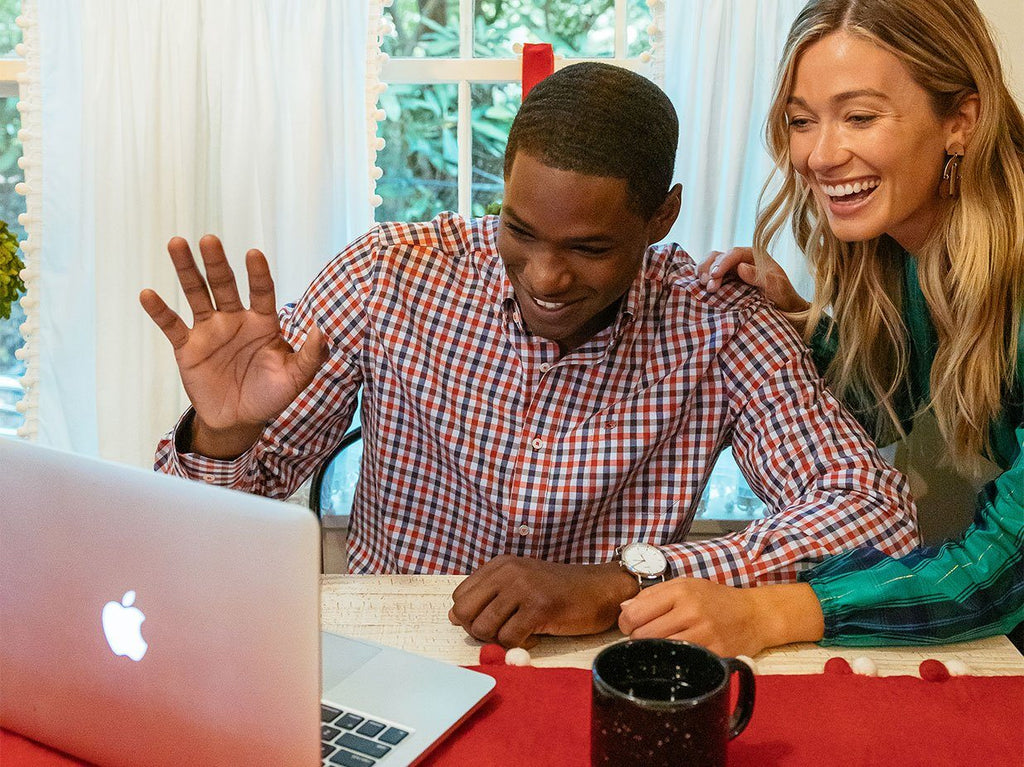 Man and woman smiling and waving at computer camera.