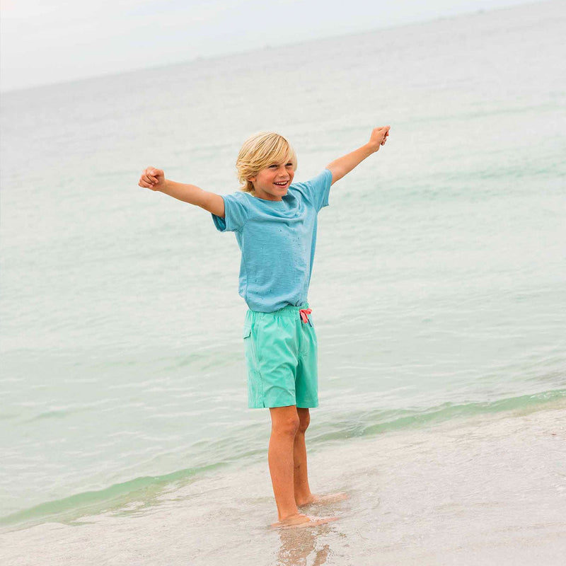 kids standing in front of ocean in solid swim trunk and t-shirt