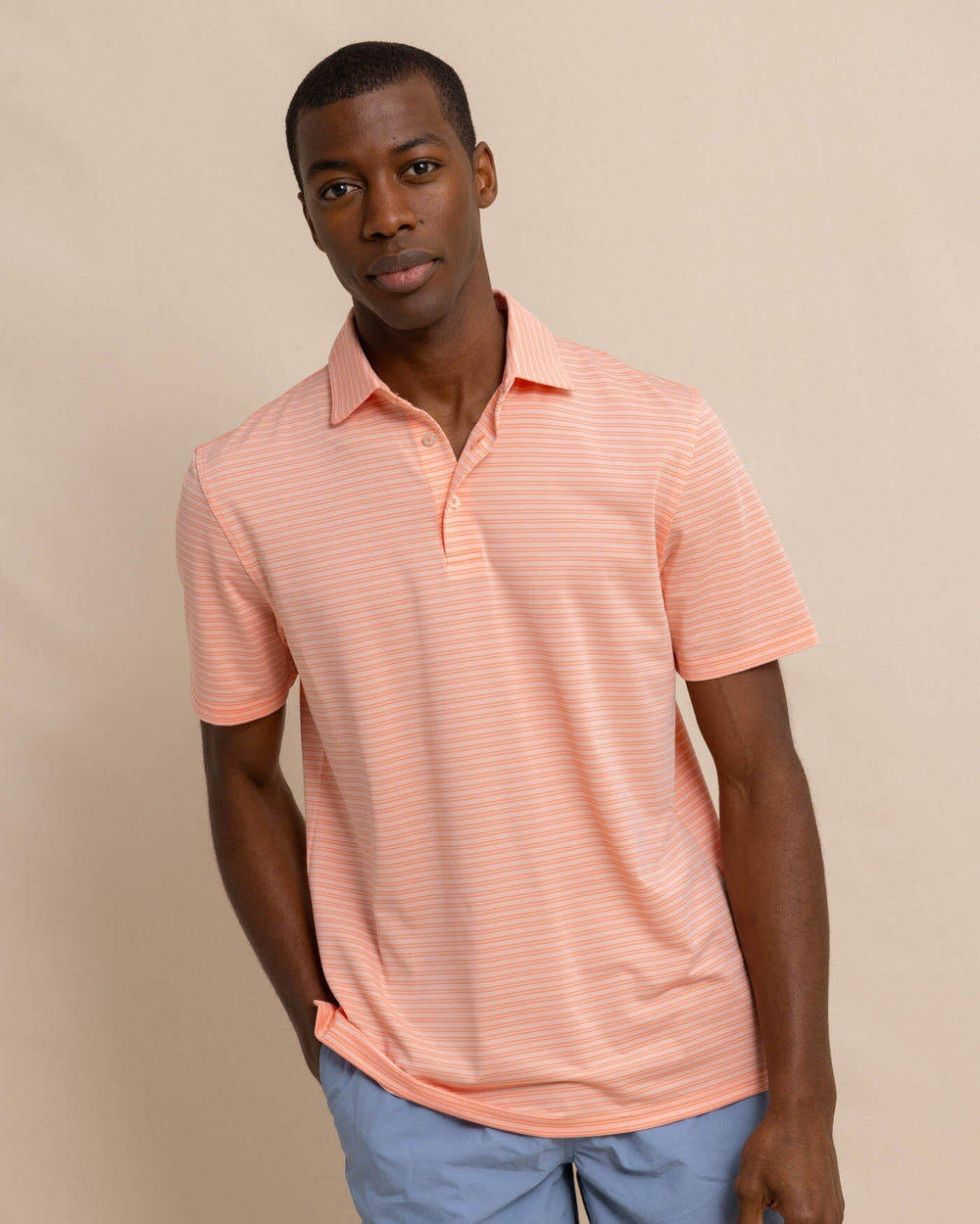 The front view of the Southern Tide brrr eeze Beattie Stripe Performance Polo by Southern Tide - Apricot Blush Coral